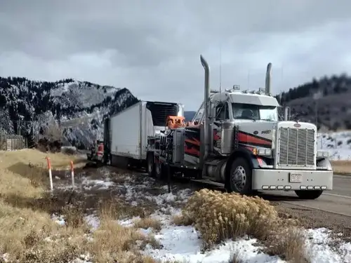 Heavy wrecker recovering a commercial tractor-trailer in winter conditions